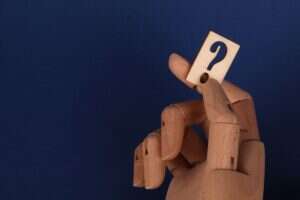 Wooden hand holding a question mark block against a blue background