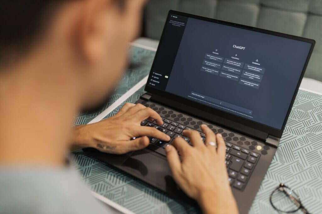 Person typing a prompt into an AI chatbot on a laptop
