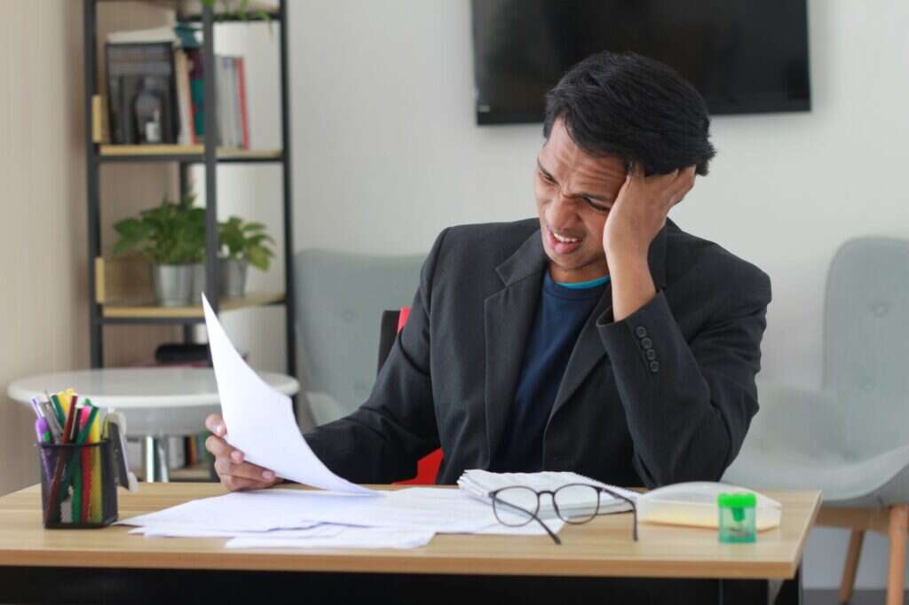 Frustrated businessman reviewing a document at his desk